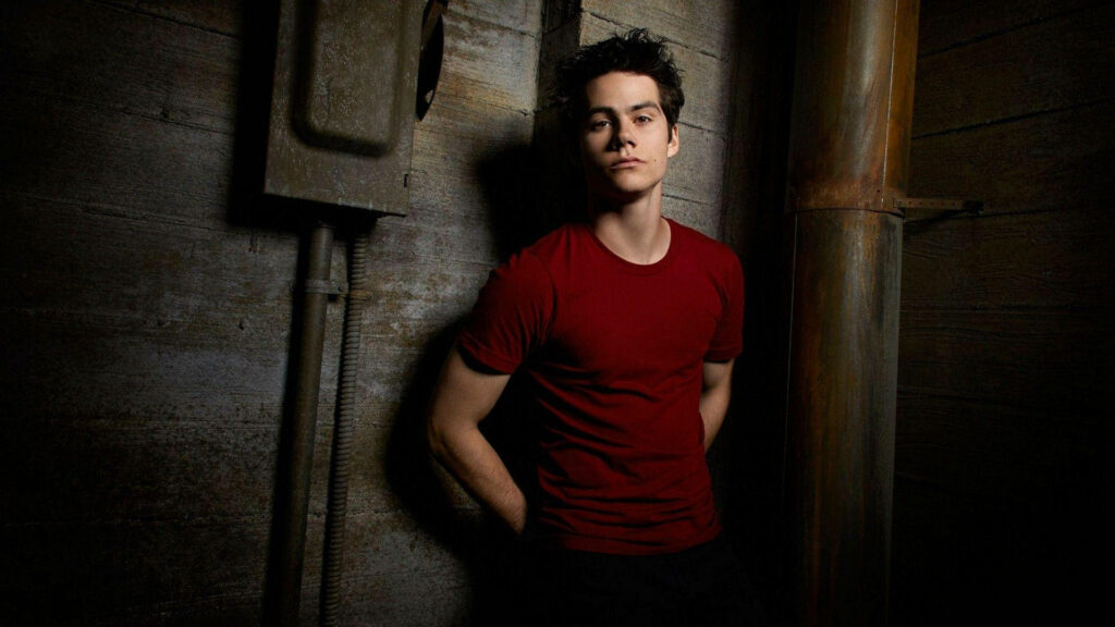 Dylan OBrien in red shirt against rustic wooden wall moody industrial background wallpaper