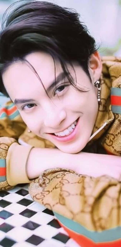 Dylan Wang in classic Gucci jacket with red green stripes smiling against pastel background wallpaper
