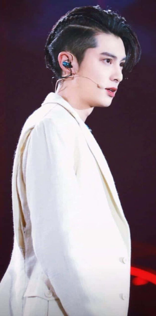 Dylan Wang performing live in white coat with modern microphone vibrant stage lighting wallpaper