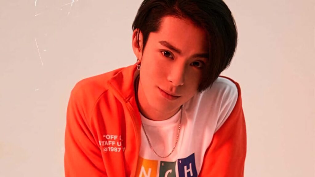 Dylan Wang confident in red orange jacket and white graphic t shirt warm toned modern style wallpaper