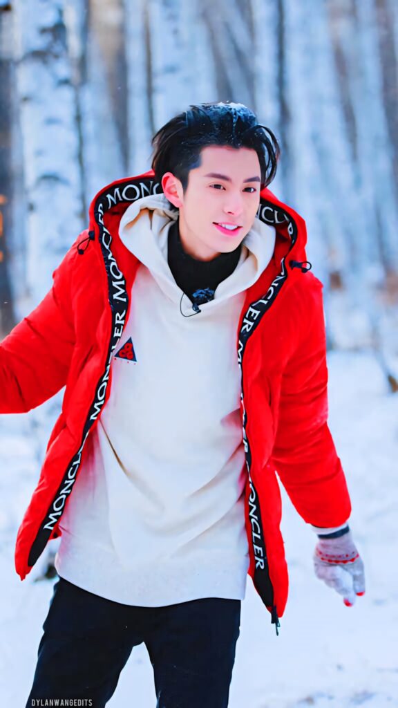Dylan Wang in red jacket and cream hoodie smiles in snowy forest winter background wallpaper