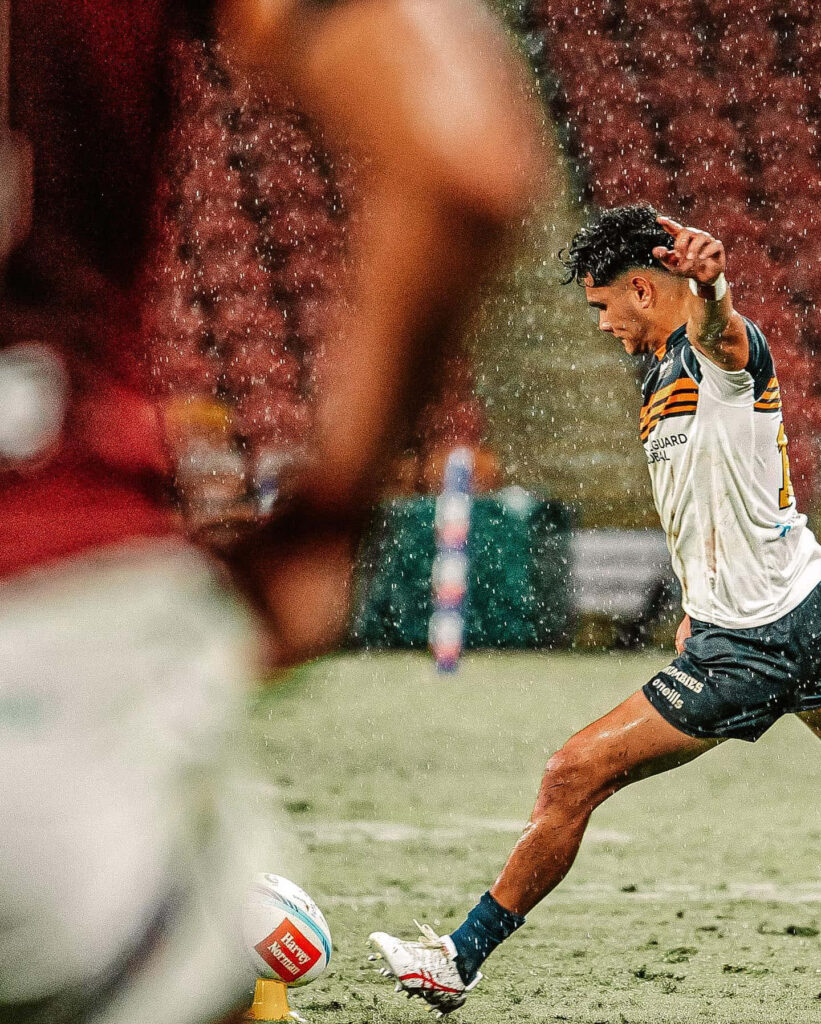 ACT Brumbies rugby player in action with gold navy white colors in rainy stadium match wallpaper