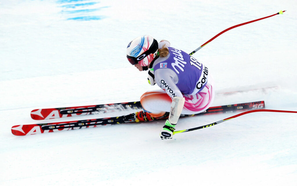 Alpine Skier Tucked Cornering: Dynamic Snowy Wallpaper Background