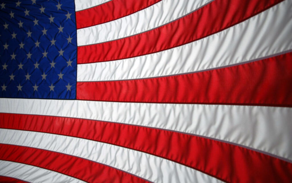 American flag wallpaper with vivid stars and stripes flowing in dynamic wave pattern background