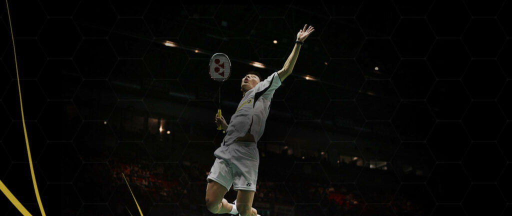 Dynamic Badminton Player in Crisp White Attire Dominating the Court amidst Vibrant Yellow Streaks Wallpaper