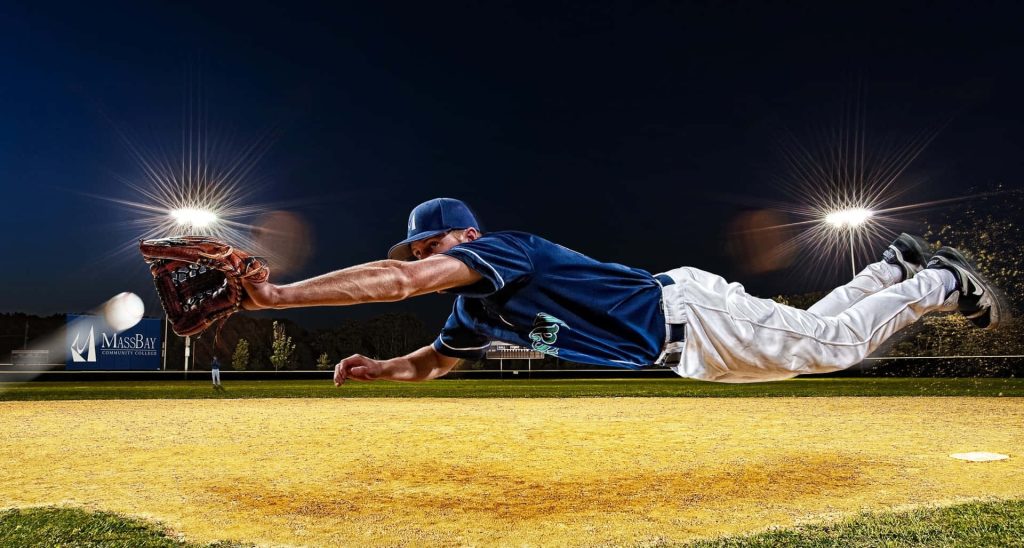 Baseball player diving horizontally for a catch at MassBay Community College under lights Wallpaper