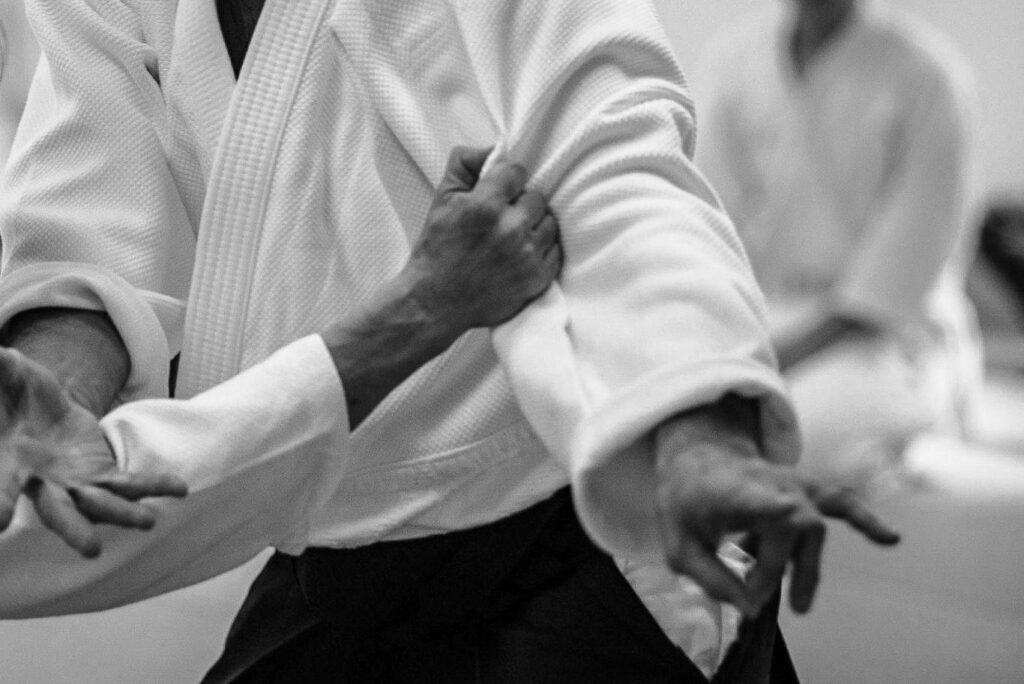 Black and white Aikido wallpaper showing intense martial arts technique and focused motion