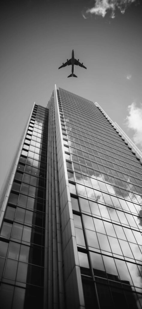Dramatic Black and White Skyscraper Wallpaper with Airplane