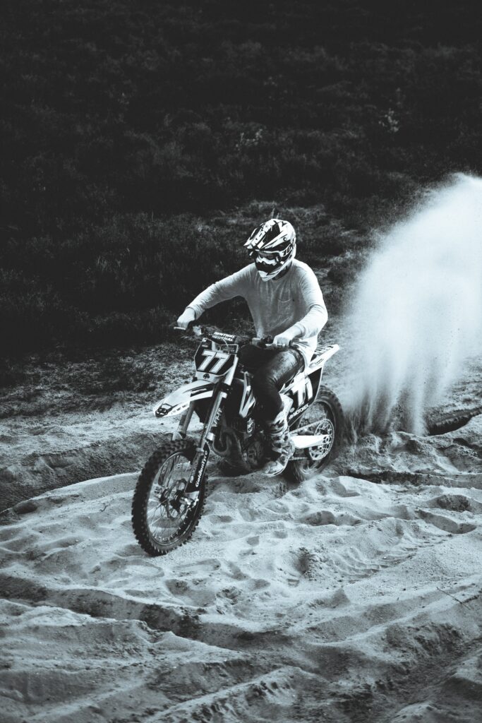 Dynamic Motorcyclist on Sandy Terrain: Black and White Rally Wallpaper