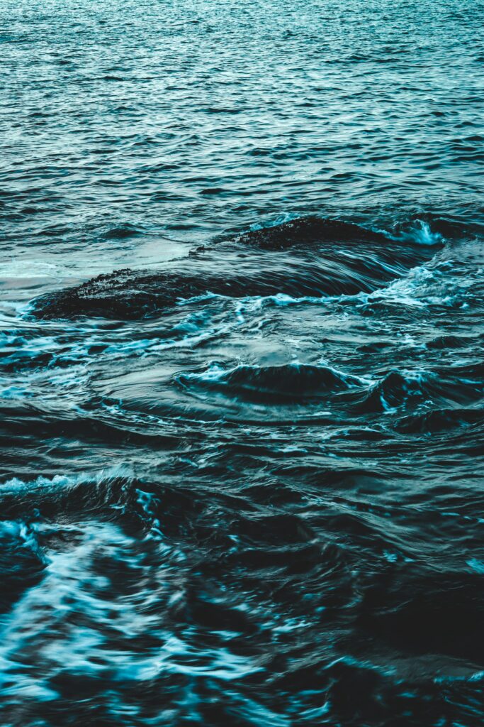 Rolling blue ocean waves with gentle water spray creating a calming sea wallpaper background