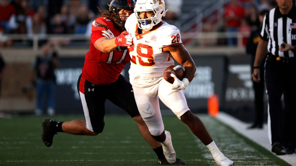 Breece Hall white jersey breaking tackle intense football action dynamic athleticism wallpaper
