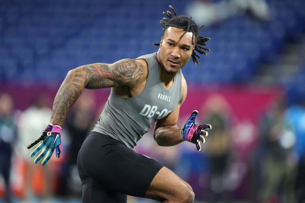 Brian Branch NFL combine action wallpaper showing muscular athlete in vibrant stadium background
