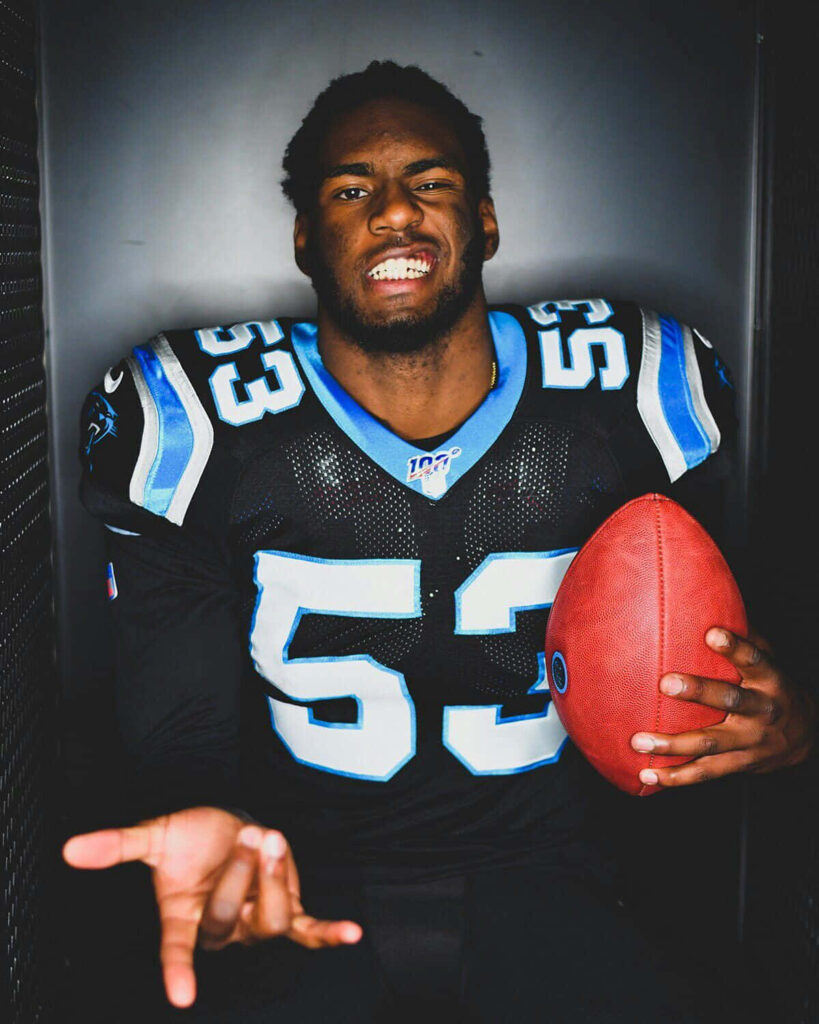 Brian Burns Carolina Panthers wallpaper intense portrait holding football bold black blue white colors