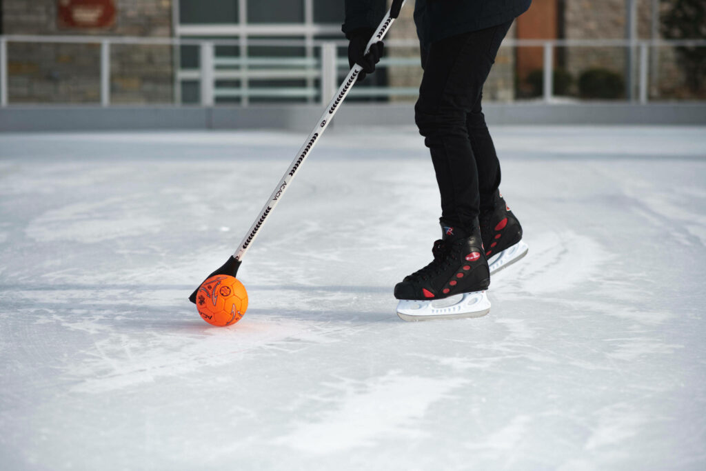 Dynamic Bromball Action Wallpaper: Player with Orange Ball on Ice
