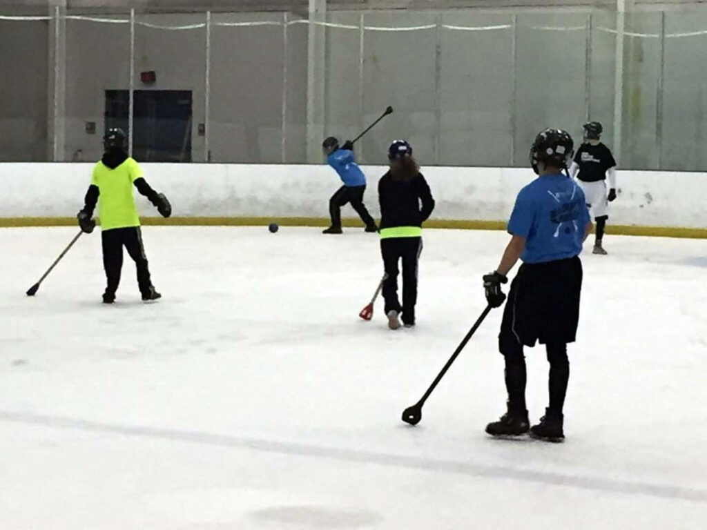Dynamic Teamwork in Broomball: Energetic Players on Ice Wallpaper