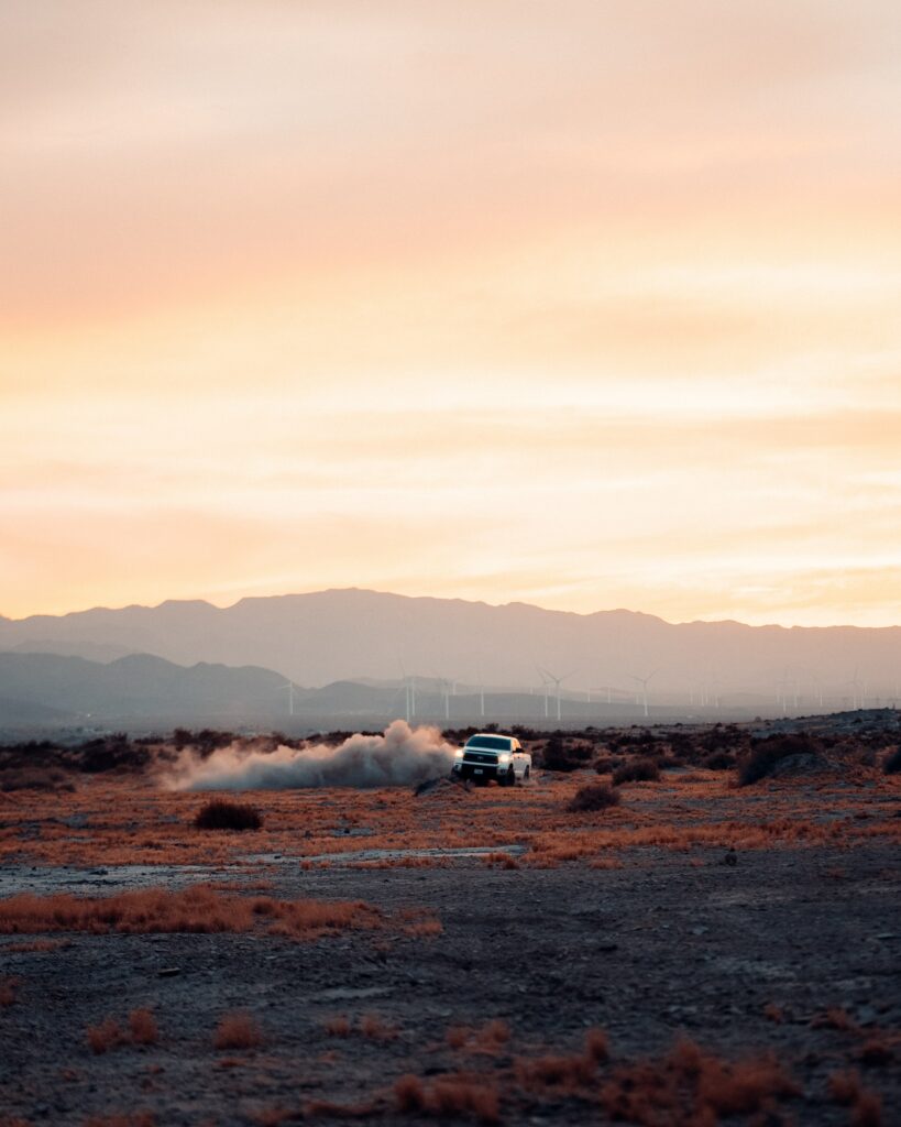 Dynamic Car Drifting in Dusty Desert at Sunset - Adventure Awaits Wallpaper