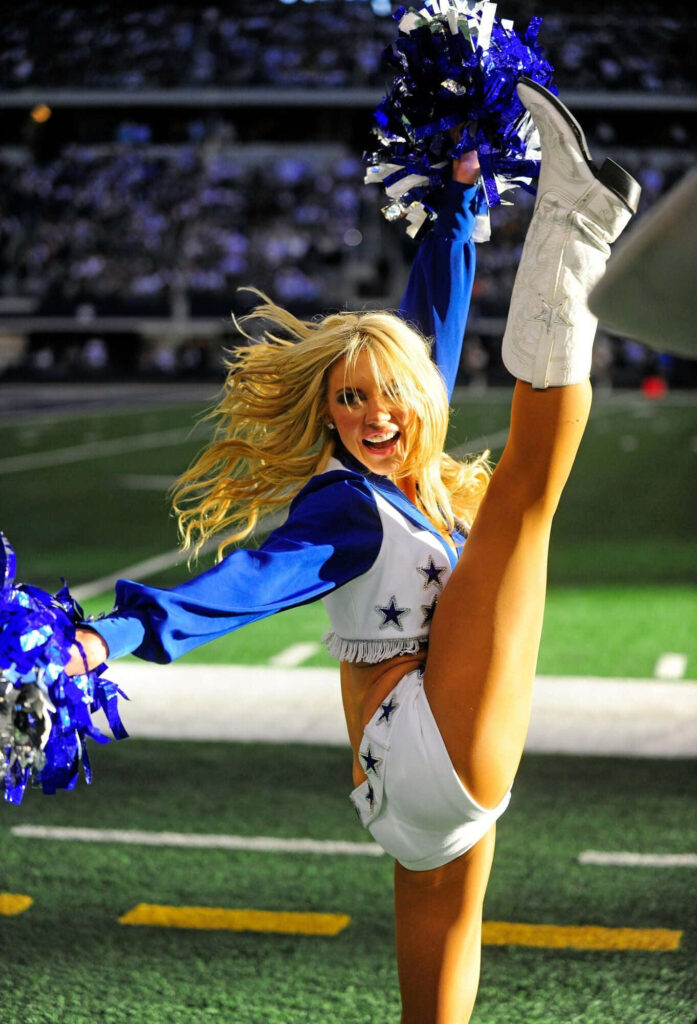 Vibrant Cheerleader High Kick Wallpaper on Football Field