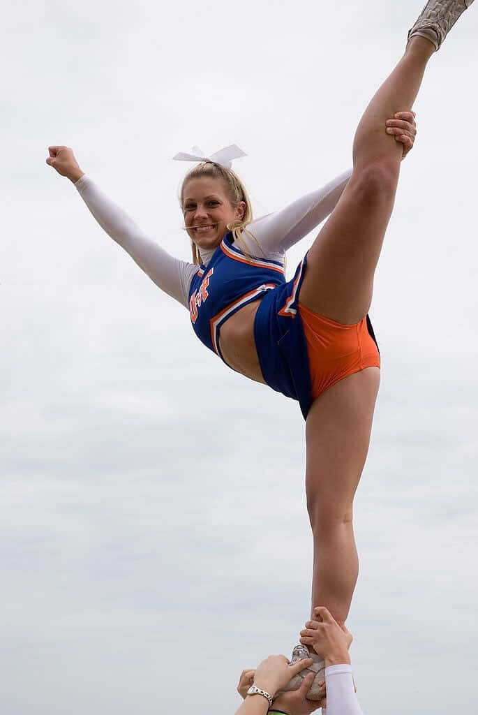 Dynamic Cheerleader Stunt Wallpaper: Flexibility & Team Spirit