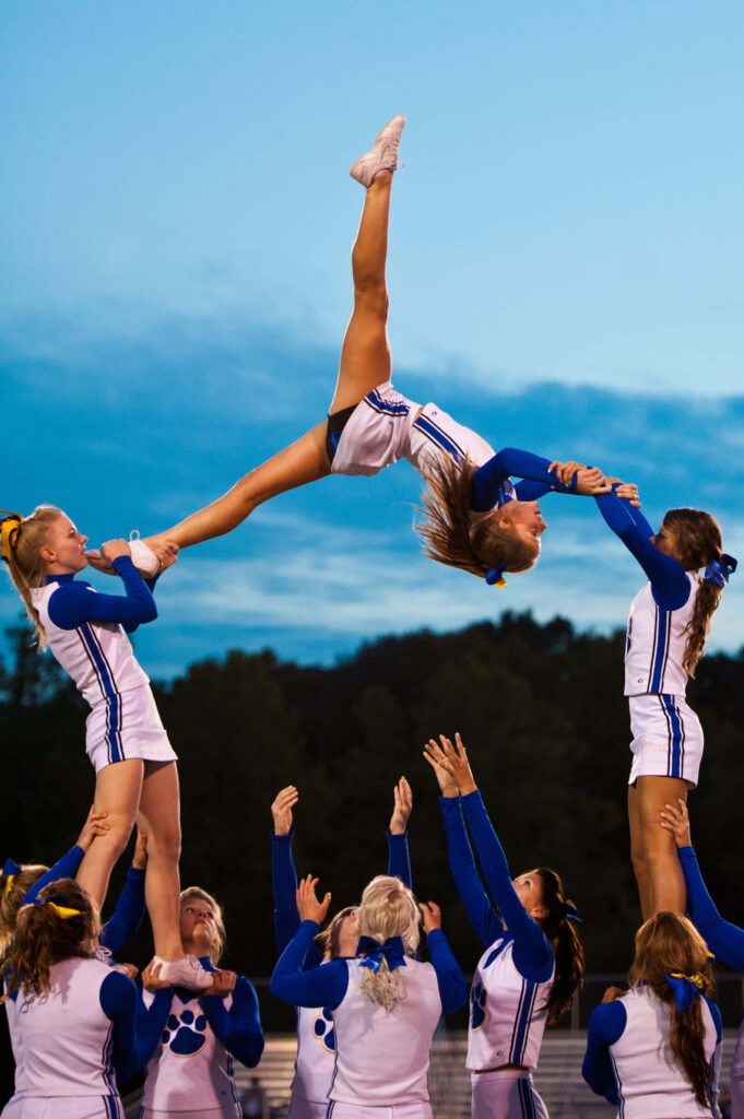 Cheerleaders Performing Impressive Stunt - Vibrant Evening Sky Wallpaper