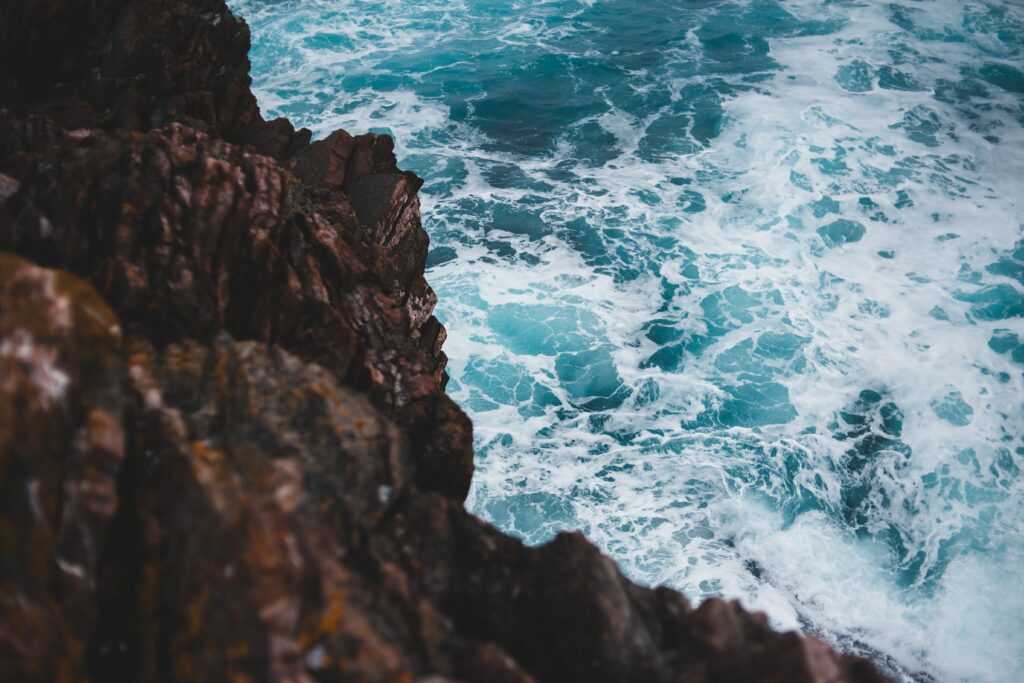 Dynamic ocean waves crashing on rugged rocks coastal wallpaper background vibrant blues
