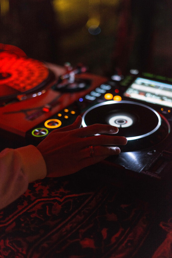 Close-up of hand mixing on modern DJ controller with vibrant red and yellow lighting nightlife background Wallpaper