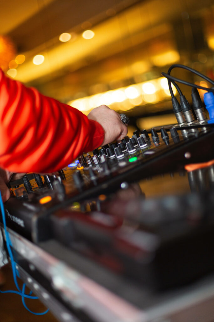 Close-up of DJ hand adjusting vibrant glowing mixing console controls in lively nightlife setting Wallpaper