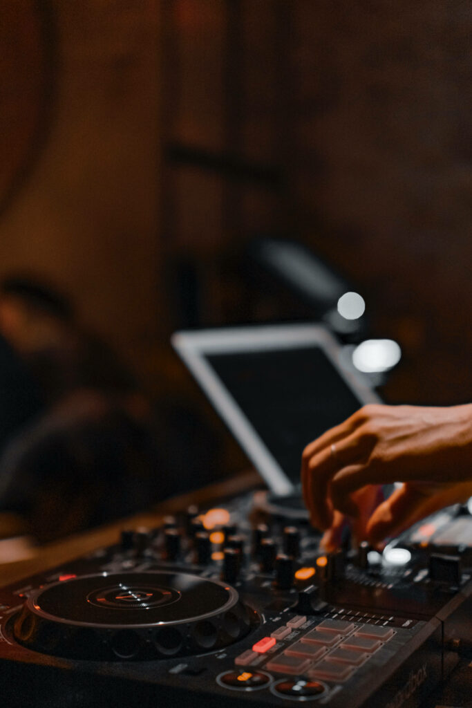 Close-up of DJ hand mixing tracks on controller with tablet in warm vibrant nightlife scene Wallpaper