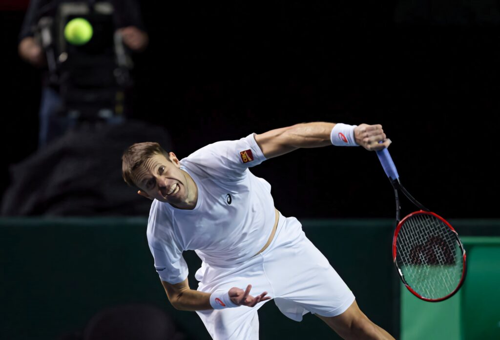 Pro tennis player Daniel Nestor mid-serve showcasing focus power and athletic form on court Wallpaper