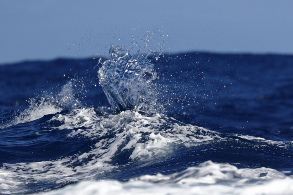 Dynamic deep blue ocean waves with foamy spray creating a vibrant sea wallpaper background