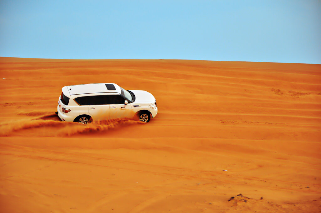 Adventure Wallpaper: White Car in Vast Sandy Desert Landscape