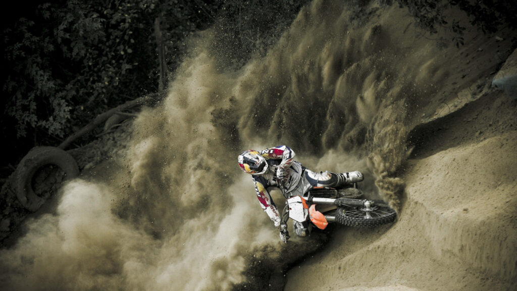 Motocross rider carving a dirt curve kicking up dust in dynamic high-speed action wallpaper