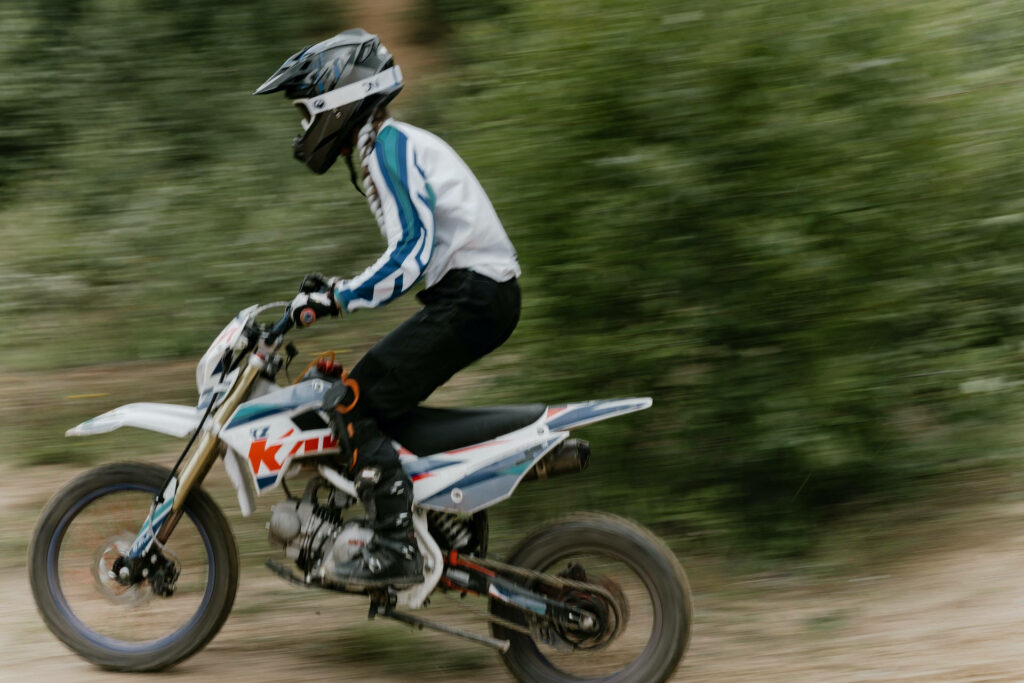 Dirt bike speeding through green landscape with motion blur highlighting off-road adventure energy Wallpaper