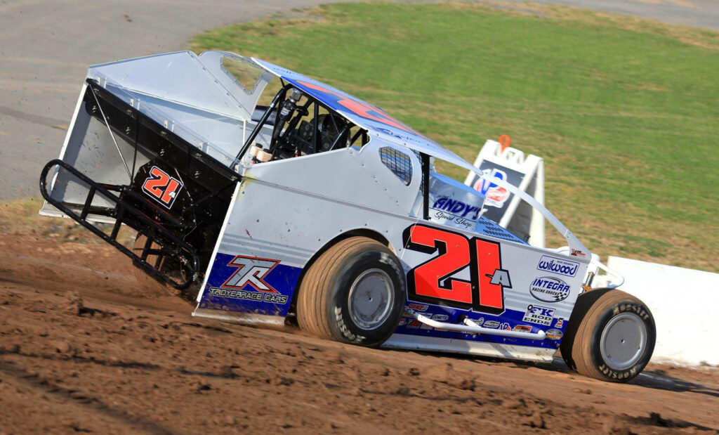 Dirt car number 21 with blue red accents drifts on clay track kicking up dust in high-speed race Wallpaper