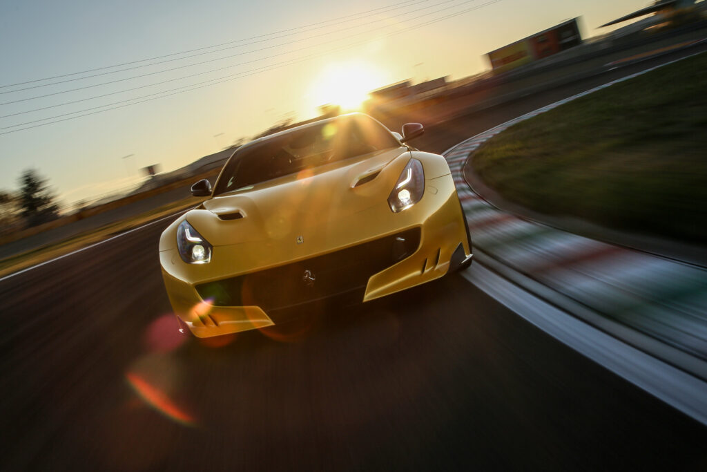 Ferrari F12 in Vibrant Yellow Racing at Sunset - Dynamic Wallpaper