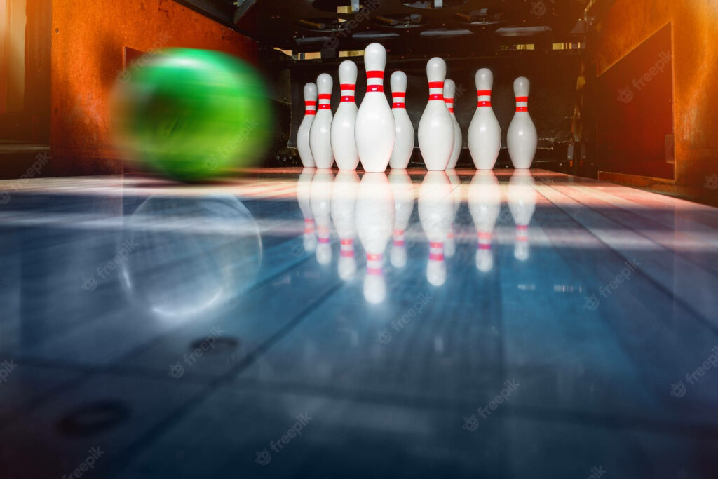 Glossy green bowling ball speeding towards white pins on polished wooden lane with motion blur Wallpaper
