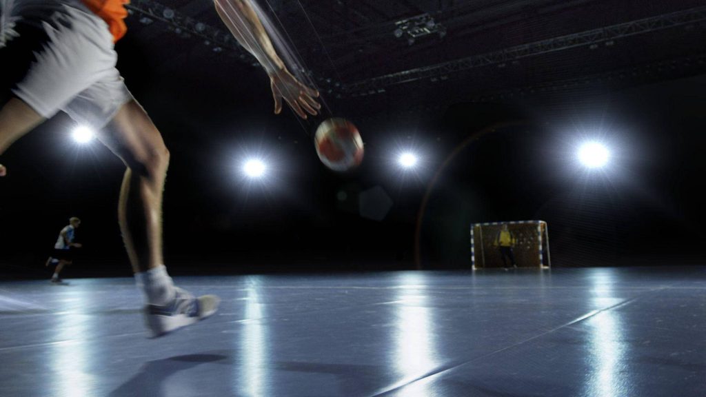 Handball player shooting on dimly lit court with dramatic spotlights and glossy floor wallpaper