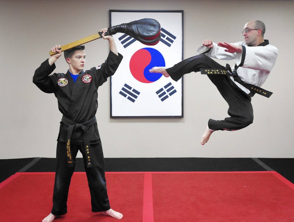Martial artist performing flying side kick in Hapkido dojo with South Korean flag backdrop wallpaper