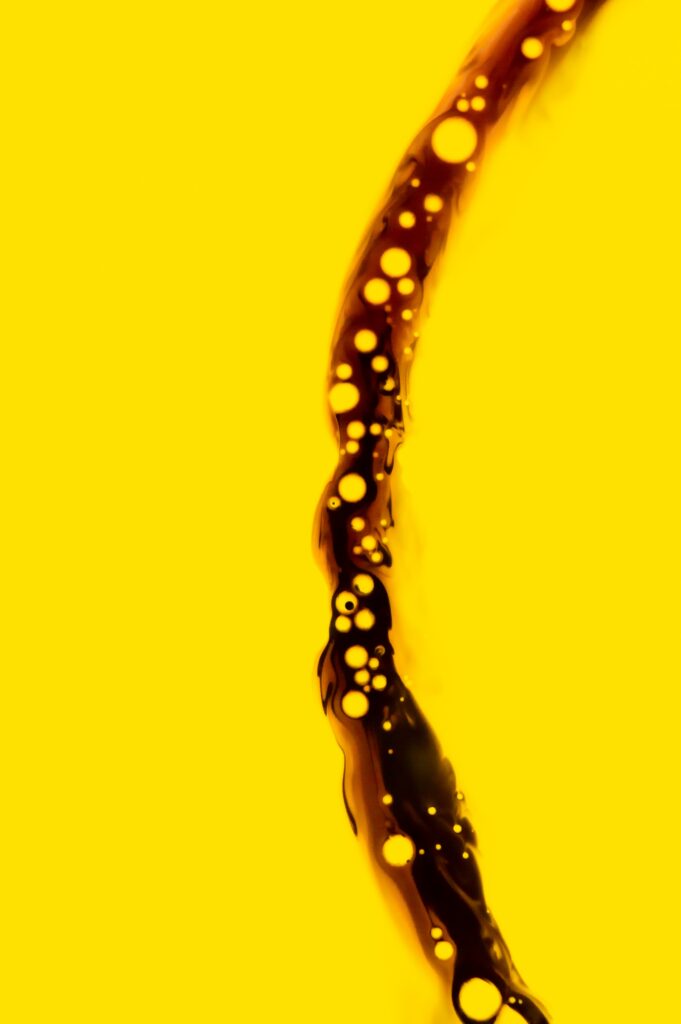 Dynamic Dark Liquid Jet Wallpaper with Air Bubbles on Yellow Background