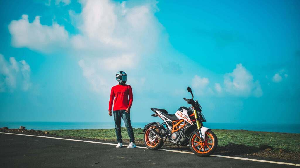 Vibrant KTM Duke 390 Wallpaper with Helmeted Rider in Scenic Landscape