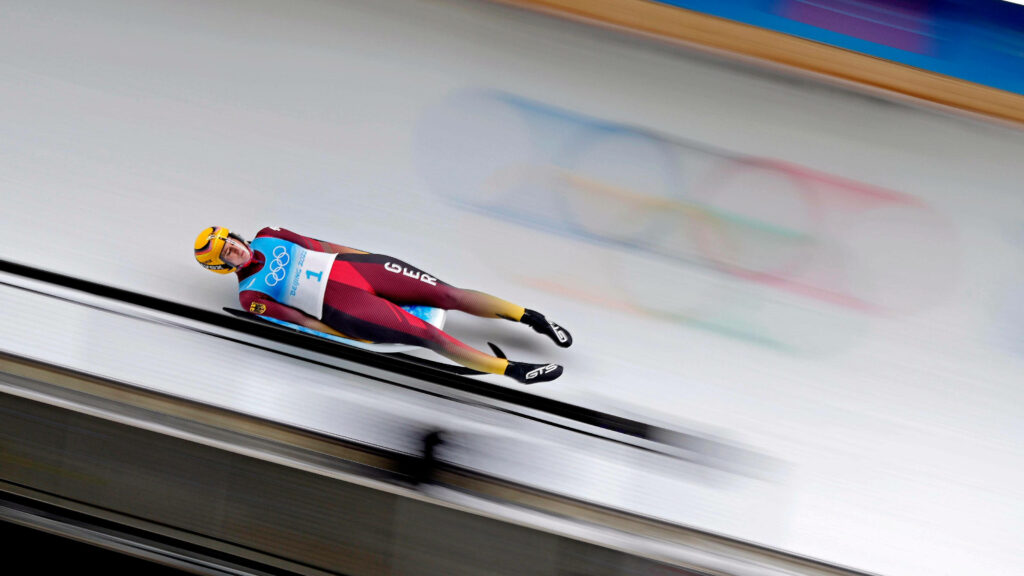 Fearless Luge Athlete: Thrilling Dynamic Winter Wallpaper Background