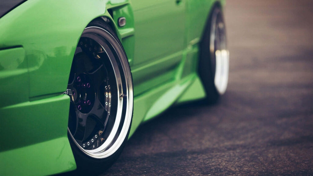 Capturing the Dynamic Essence of a Matte Green Stance Jdm Car with Turning Wheels Wallpaper
