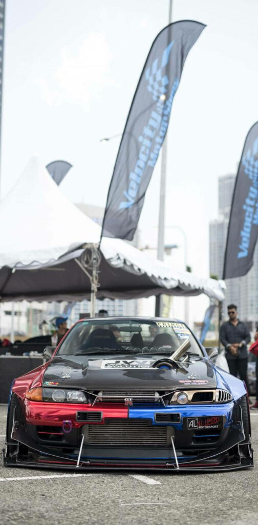 Vibrant Modified Car Wallpaper at Outdoor Event with City Backdrop