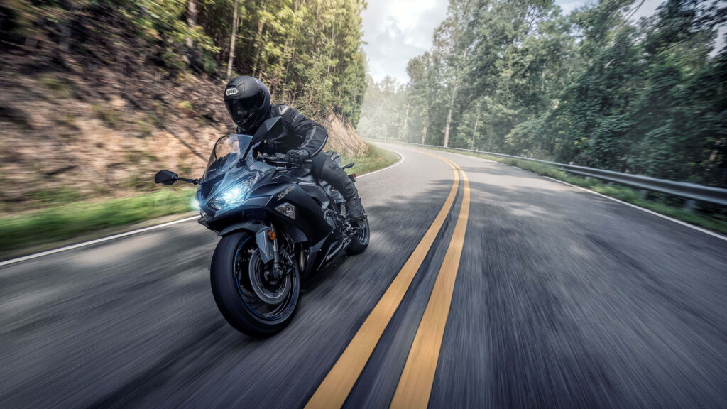 Thrilling Motorcycle Wallpaper: Rider in Lush Green Forest