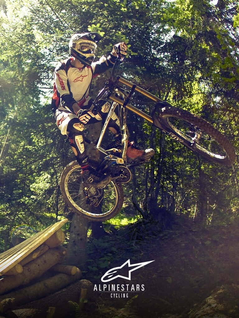 Thrilling Mountain Biker Stunt Wallpaper in Lush Forest