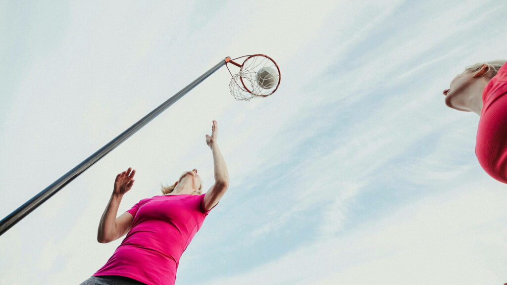 Dynamic Netball Player Wallpaper: Aim High Under Blue Skies