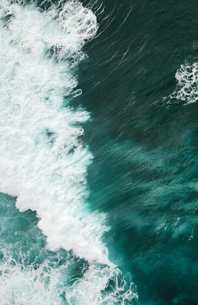 Aerial view of powerful blue ocean waves with white foam showcasing dynamic sea movement Wallpaper