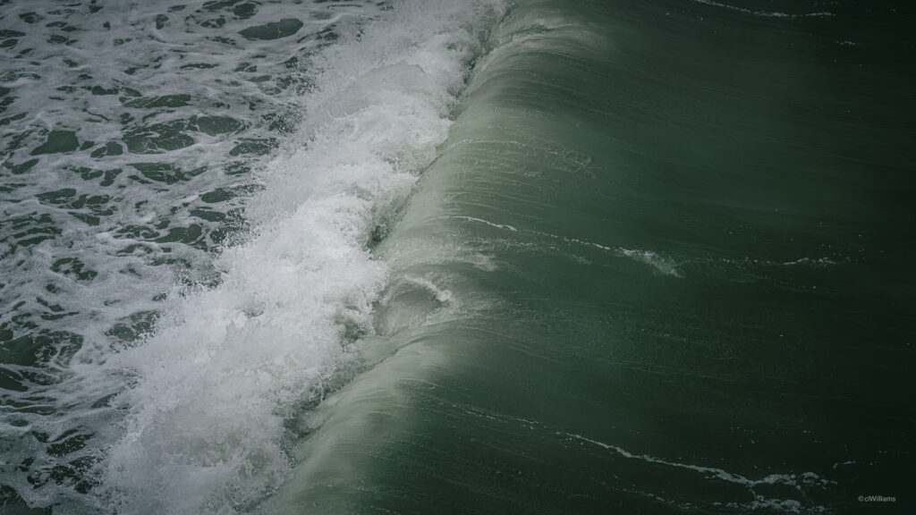 Close-up of powerful ocean wave with swirling water cascading foam and deep green tones wallpaper