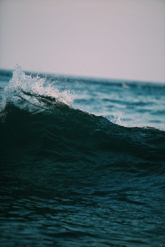 Dynamic ocean wave with foamy spray and deep blue water showcasing natural beauty Wallpaper