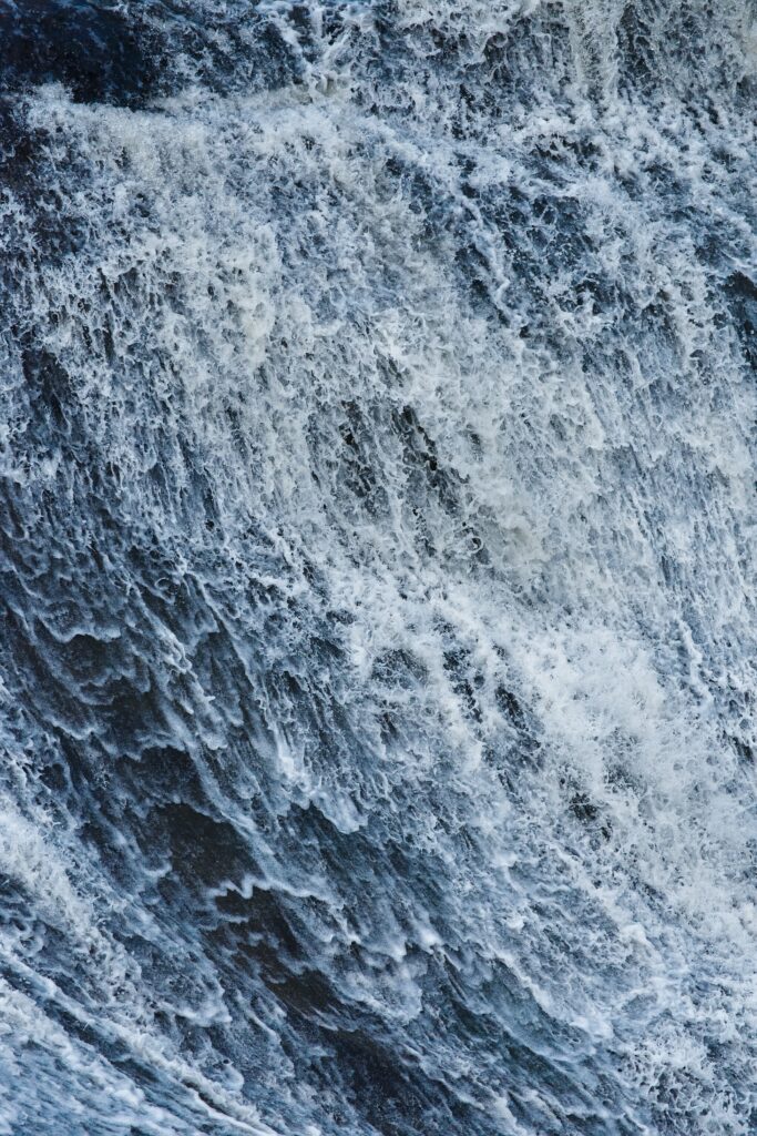 Dynamic ocean wave wallpaper with swirling water foamy textures and energetic blue white sprays
