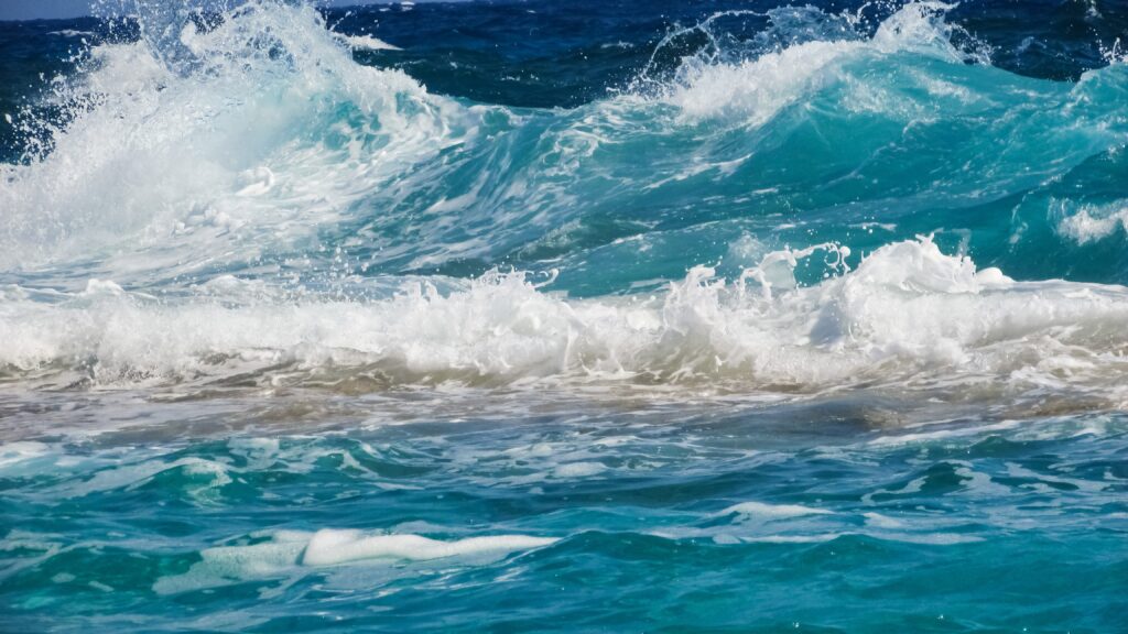 High-resolution wallpaper of vibrant blue and turquoise ocean waves crashing with white foam